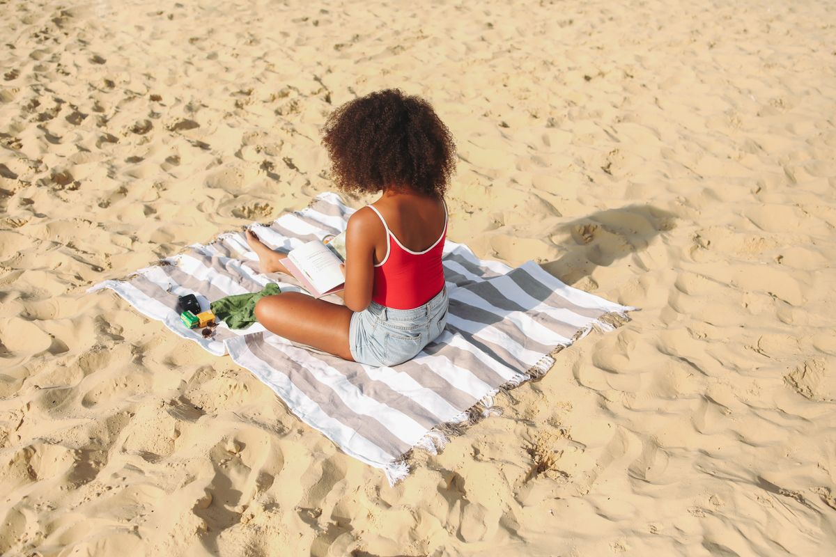 Personne assise sur une serviette, dos et epaules exposes au soleil