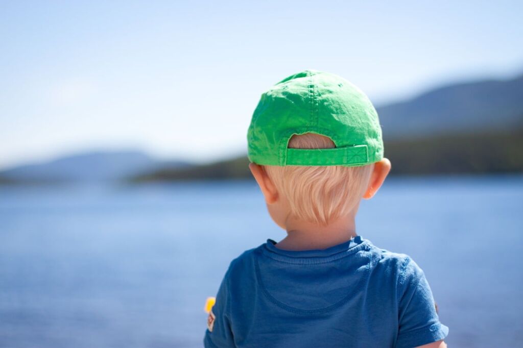 Enfant de dos portant une casquette, les oreilles et la nuque en plein soleil