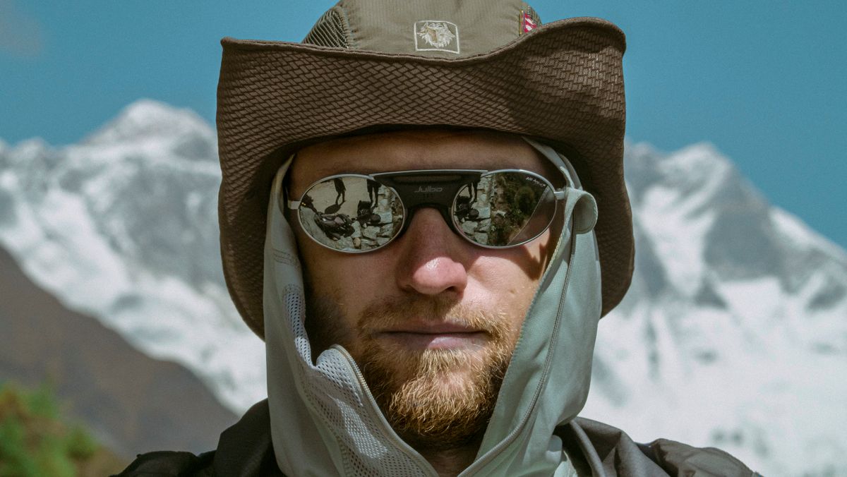 Homme portant des lunettes de soleil enveloppantes devant des sommets enneiges