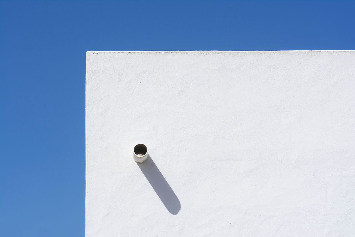 Mur blanc sous un ciel bleu profond, ombre tranchee