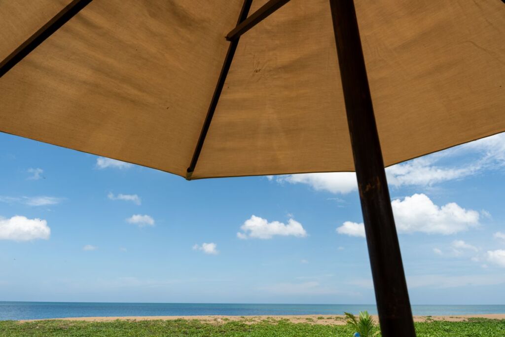 Vue depuis l'ombre d'un parasol de plage vers la mer et le ciel en pleine lumière