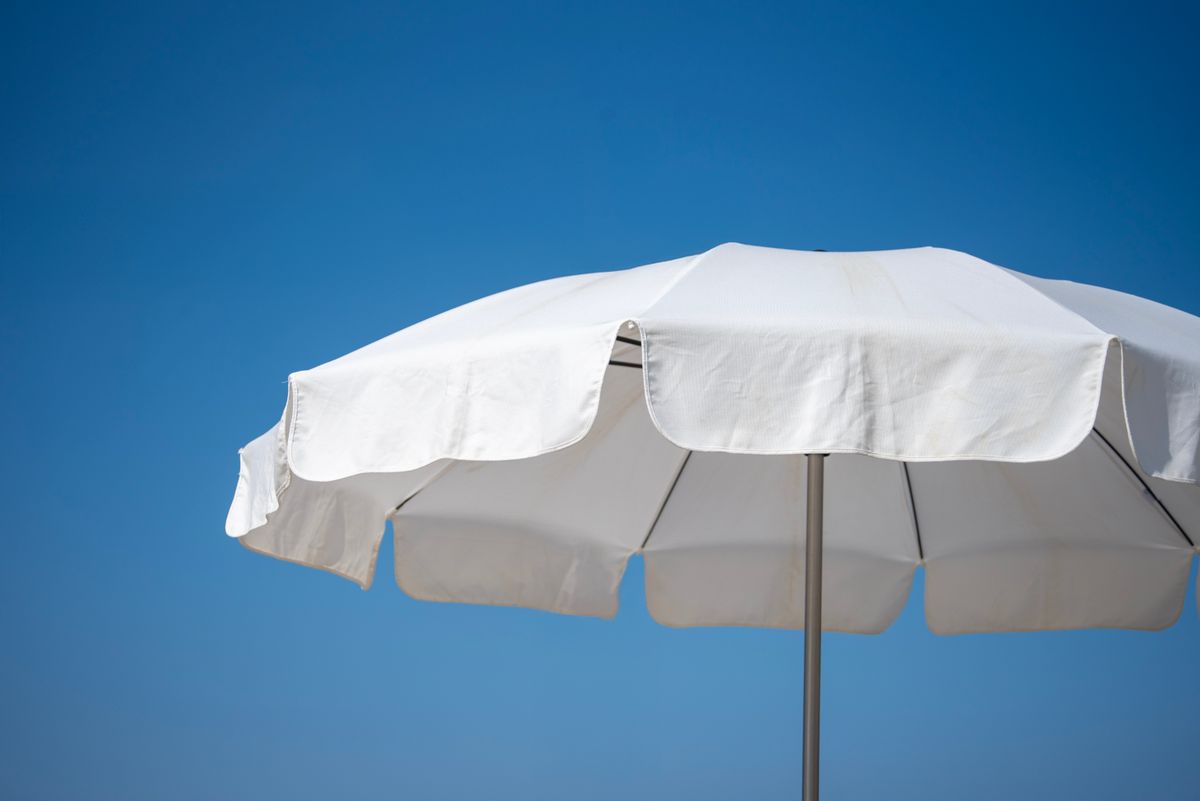 Parasol blanc ouvert sous un ciel bleu