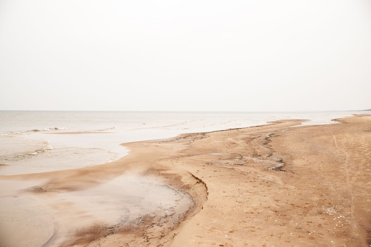 Plage de sable déserte sous un ciel entièrement voilé de blanc