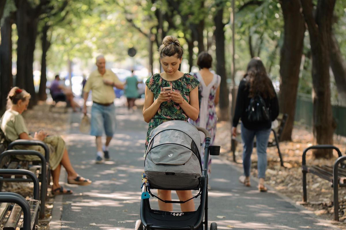 Une poussette avançant dans une allée de parc ombragée par les arbres