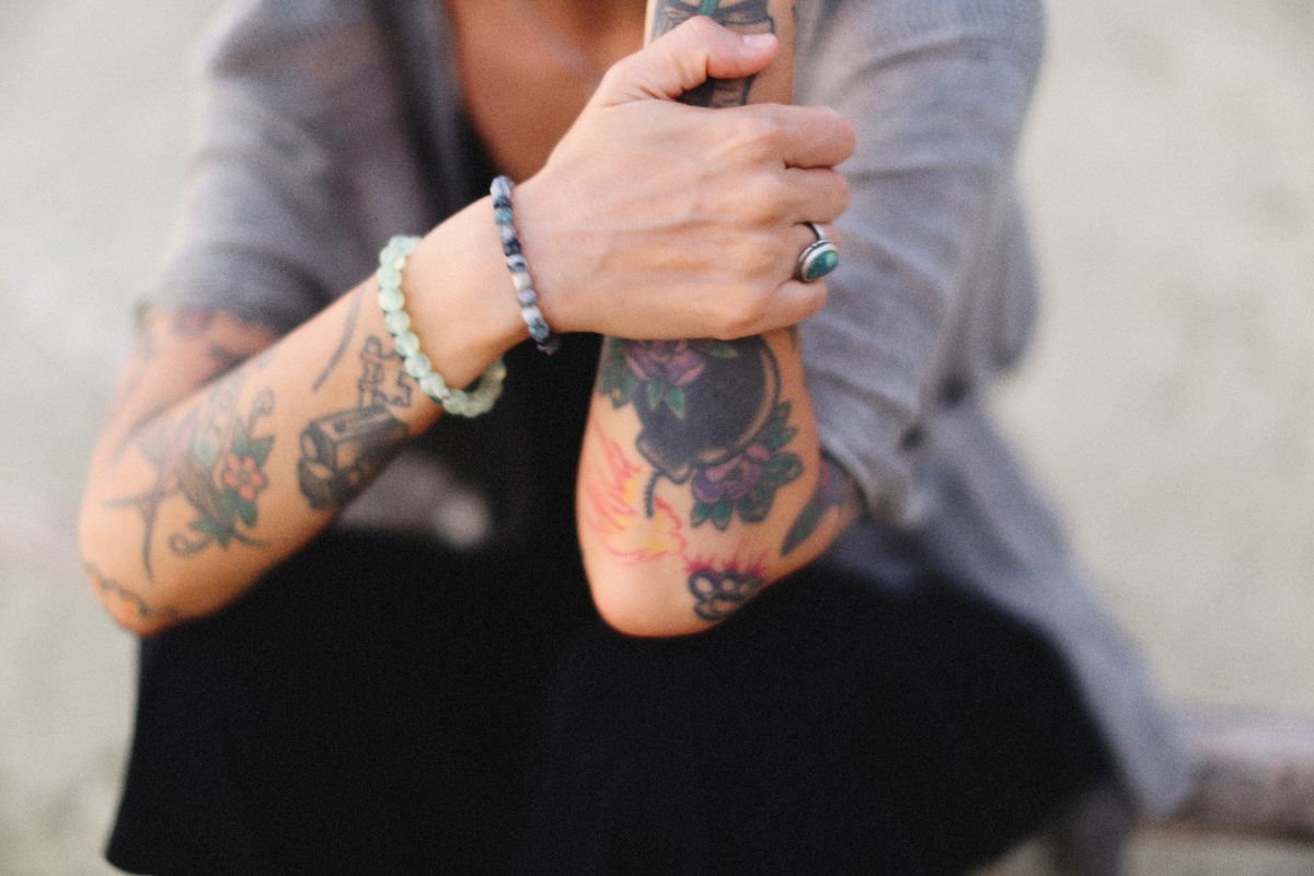 Deux avant-bras portant des tatouages colores, en exterieur