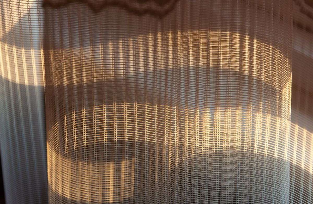 Toile à trame ouverte en contre-jour, la lumière passe entre les fils